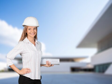 Female architect holds architectural blueprints posing outdoor
