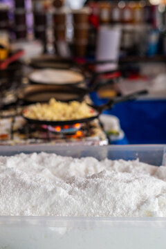 Rio de Janeiro, Brazil - 22 May 2026: View of tapioca flour in a container at Square Nossa Senhora da Paz with a street food stall cooking pancakes in the background.