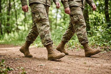 Fototapeta premium Two army soldiers walk in uniform on a dirt path outdoors