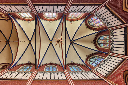Bad Doberan, Germany - 19 July 2025: View of the vaulted ceiling of the Doberaner Munster with red brick ribs, stained glass windows, and a hanging star ornament.
