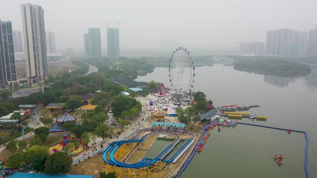 Foggy Aerial View of Lakeside Urban Amusement Park with Ferris Wheel