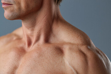 Naklejka premium Muscular male shoulder and upper torso with defined collarbone and textured skin in soft daylight, subtle emotion of calm confidence