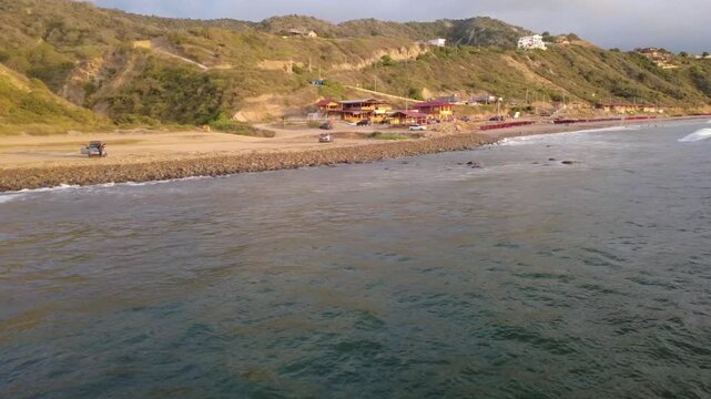 Side view of Liguiqui beach in Manabi, just at sunset, smooth shots over the rocks on the beach shore, on the horizon you can see the famous arid cliffs of South America, Ecuador