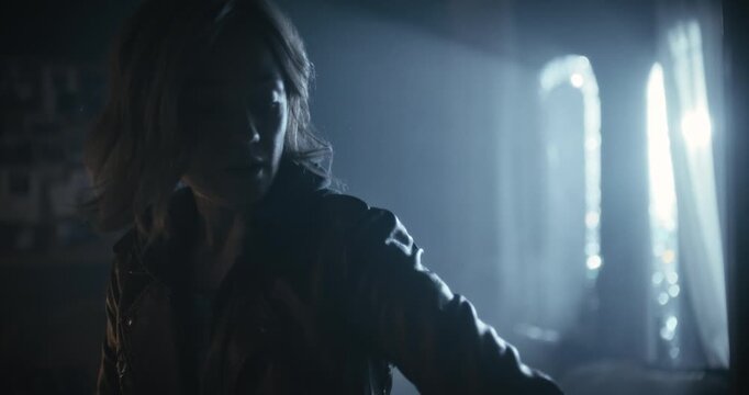 Cinematic silhouette of woman with flashlight entering spooky, foggy room and propping door open