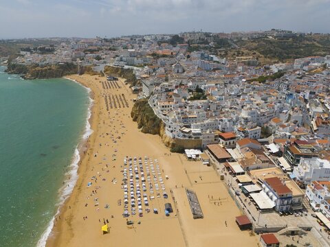Aerial view of a coastal town with a sandy beach on which numerous parasols and deckchairs can be seen, Albufeira, Faro, Algarve, Portugal