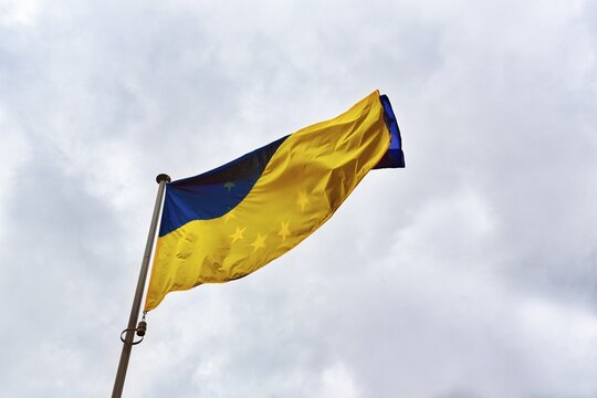 European flag shines through Ukrainian flag, flutters in cloudy sky, symbol, EU, France