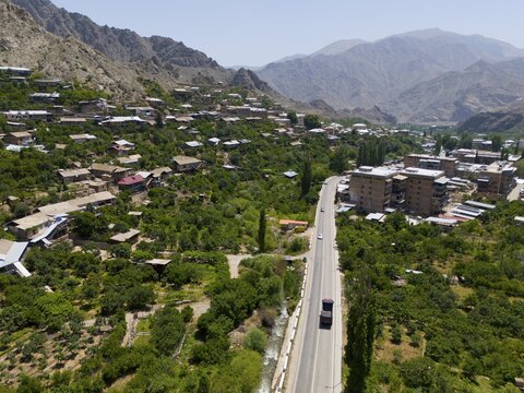 Village with a road winding through a mountainous landscape with green vegetation, aerial view, Meghri, Syunik province, mountains in the background are located in Iran, Armenia, Asia