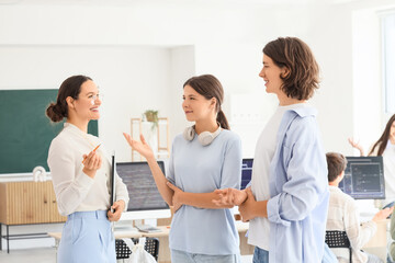 Fototapeta premium Female teacher talking to teenage students at school computer lab