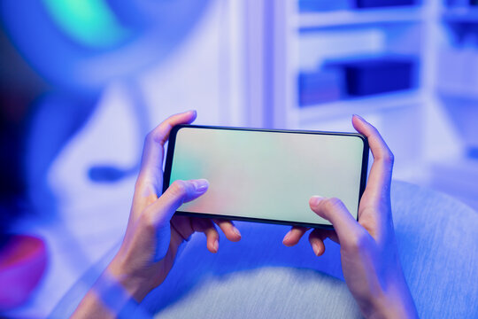 Hands holding smartphone with blank screen while playing mobile game, online gaming and digital entertainment concept.
