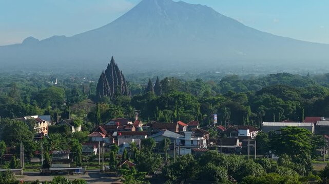 Aerial view of Prambanan Temple with Mount Merapi in the background surrounded by lush trees and village houses in Kecamatan Prambanan, Daerah Istimewa Yogya, Indonesia.