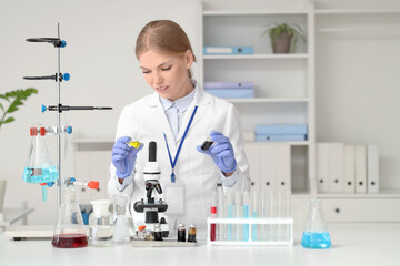 Fototapeta premium Female scientist with ampules and microscope at table in laboratory