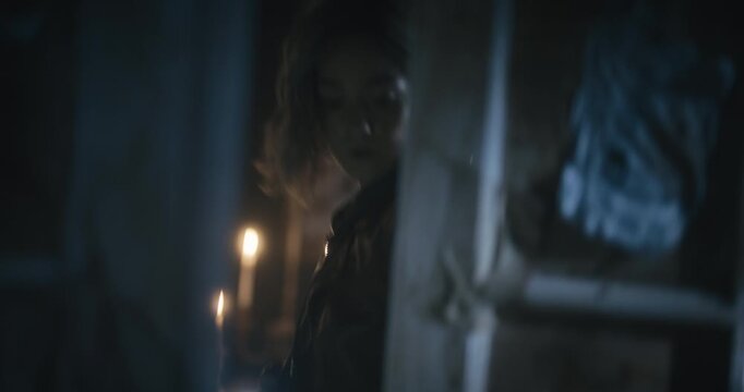 Woman with flashlight exploring haunted house and propping door open with a book - medium shot