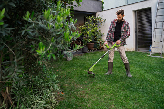 Landscaper using grass trimer in the garden 