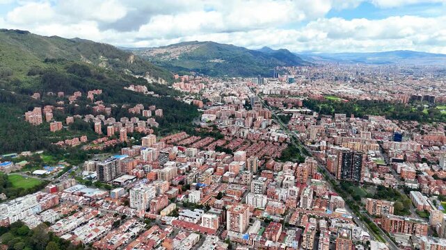Aerial shot showcasing Bogot&aacute;'s sprawling residential buildings against a backdrop of lush hills and a cloudy sky.