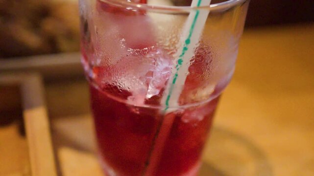 Pouring Red Roselle Juice into a Glass with Ice and Straw