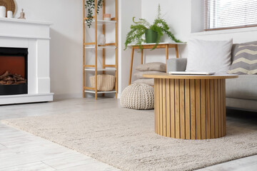 Fototapeta premium Interior of light living room with grey sofa, fireplace, coffee table and carpet
