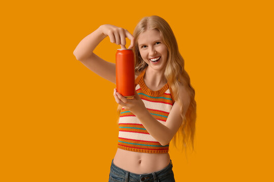 Happy young woman with can of soda on yellow background