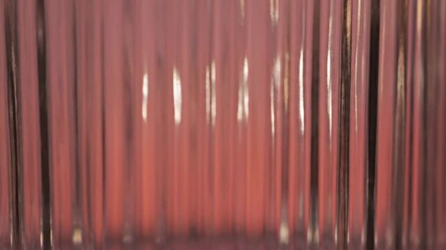 Vertical fluted glass texture with warm pink lighting.