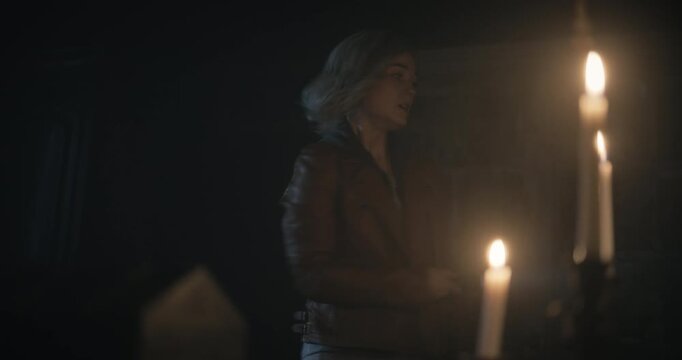 Nervous woman entering spooky, dark room as door closes behind her and she opens mysterious chest on desk - steady cam