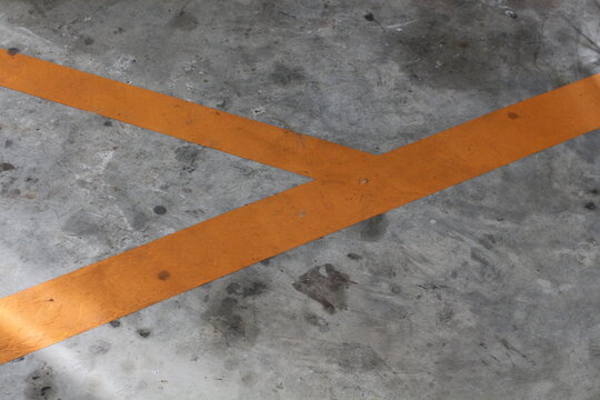 Orange directional lines painted on a weathered concrete floor surface