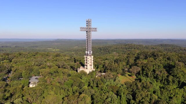 Monumental cross tower dominates Atlantic Forest landscape in Parque Tem&aacute;tico de la Cruz, Santa Ana, Misiones Province, Northeast Argentina, drone forward approach aerial shot during sunny day