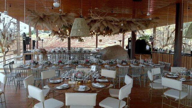 Interior of elegant restaurant with decorated dining tables, white chairs, modern design and stylish event setup in spacious venue