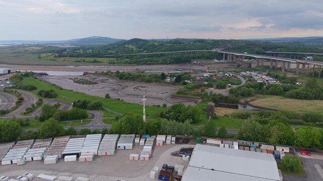Aerial View of River Neath with M4 Motorway Overpass with Industrial Hub with Shipping Containers at Low Tide.