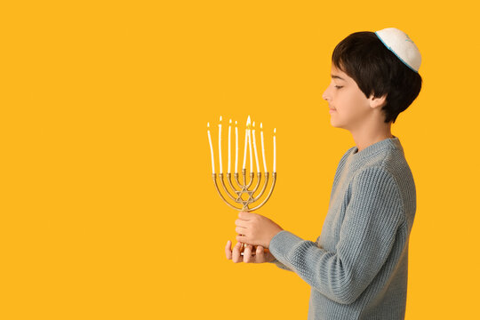 Little Israeli boy in kipa with menorah on yellow background