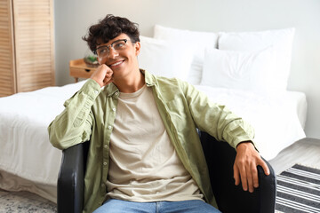 Fototapeta premium Young man with eyeglasses sitting in bedroom