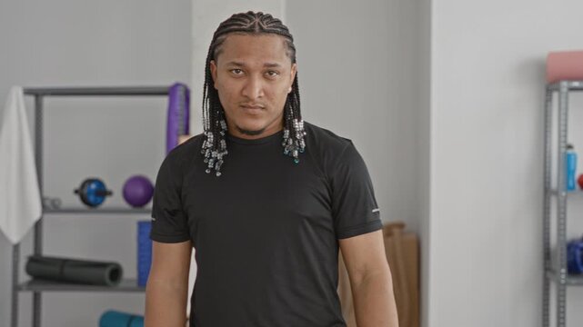 Man wearing red boxing gloves holds a guard stance and practices punching in a bright training studio; determination.