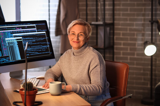 Mature female programmer working in office at night