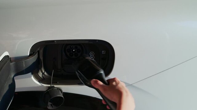 4K slow motion person charging electric car at home.	
