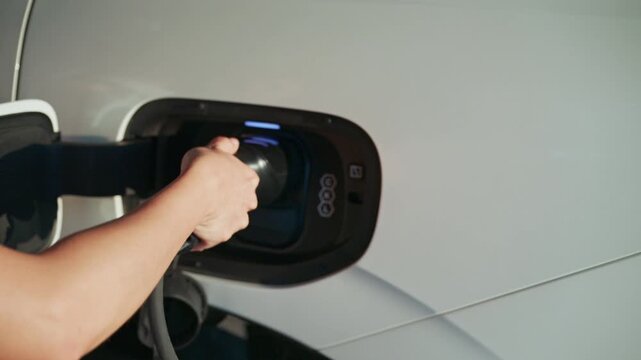 4K slow motion person charging electric car at home.	

