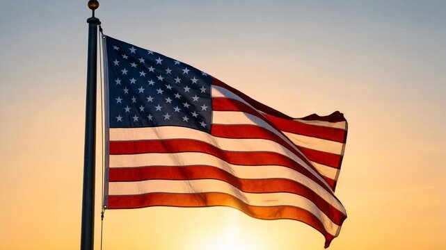 American flag waving gently on flagpole at sunset golden hour with warm glowing sky background