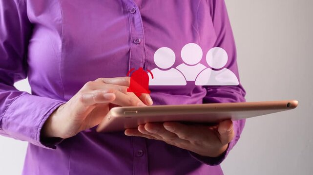 Close-up of a businesswoman interacting with her tablet, an animation of a group of people icon with a notification bell. Group notifications.
