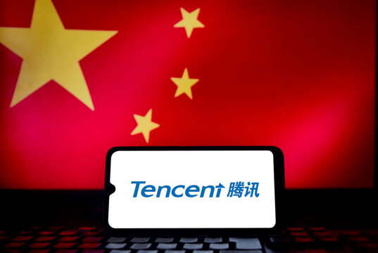 Tencent Holdings Ltd. logo on a smartphone screen with the Chinese flag in the background. Tencent is one of the world's largest technology and media conglomerates, headquartered in Shenzhen, China.