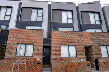 Naklejka premium A contemporary multi-storey townhouse features a combination of brick on the lower levels and render on the upper floors in Melbourne. Urban density,&nbsp; property investment, and Australian housing.