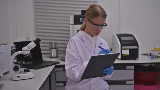 Focused Female Researcher Document Lab Experiment Data On Clipboard