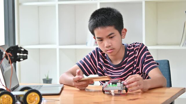 Intelligent Boy Use Mobile Phone To Test Robotic Arm On Desk