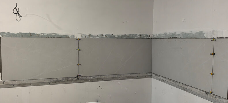 Construction work on wall with unfinished surface and installed panels in a room