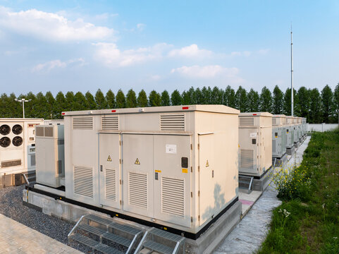 Outdoor arrangement of industrial generator sets with green trees and blue sky background