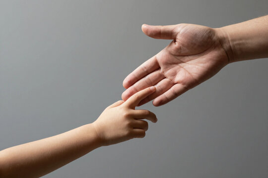 Man and children hands reach toward each other. Child and father hands isolated on gray. Small child's hand reaches for the hand man. Helping hand concept, support. Helping hand outstretched.