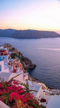 Beautiful sunset view of Oia village in Santorini island, Greece, featuring traditional white buildings with blue domes, blooming pink bougainvillea flowers, and the Aegean Sea.