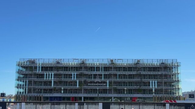 Contemporary architectural design of the Paris Orly international airport building with a plane flying over against a clear blue sky on a sunny summer day in France