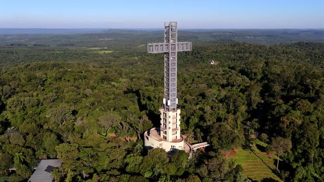 Drone aerial showcasing Santa Ana Cross rising above Parque Tem&aacute;tico de la Cruz rainforest landscape.