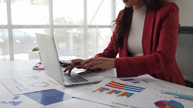 Businesswoman analyzing data charts and typing on laptop