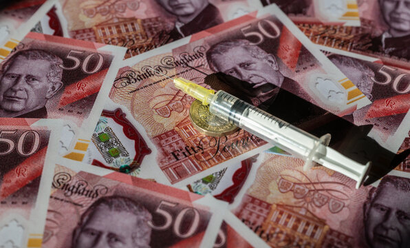 A disposable syringe against a background of 50 British pound notes