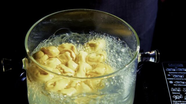 Dumplings Boiling In Boiling Water Inside Transparent Glass Pot On. Cooking Italian Tortellini Or Ravioli 