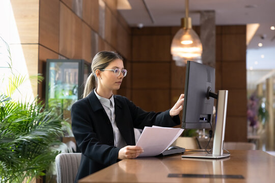 Hotel receptionist managing reservations, enters guest information into computer, handling documentation. Professional hospitality reception workflow, administrative tasks, customer service operations