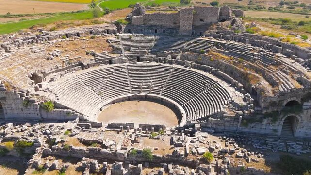 Balat, Turkey. Ancient Miletus Theatre, semi-circular stone cavea with tiered seating and arched passageways, aerial view under bright summer sun. Aerial View, Point of interest